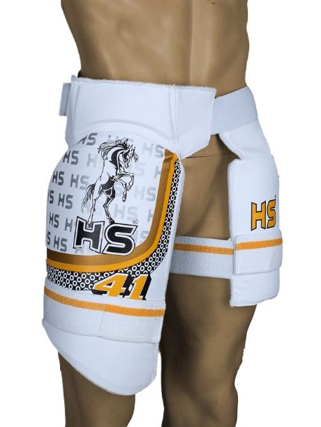A mannequin is wearing the HS 41 protective gear by HS, featuring white hip and thigh pads with orange and black details. The thigh pads display the initials "HS," graphics of a horse, and the number "41." Designed for cricket safety, this gear provides impact protection with adjustable straps for a secure fit around the hips and thighs.