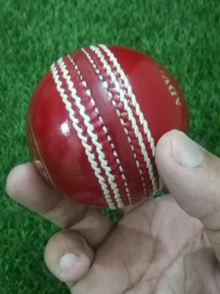 A red leather cricket ball from the "Advance Target 300 - 156g Red - Pack of 6 Balls" collection is featured against a plain white background, showcasing its prominent white hand-stitching. The ball boasts the brand name "ADVANCE" engraved in gold letters on one side, emphasizing its premium quality.