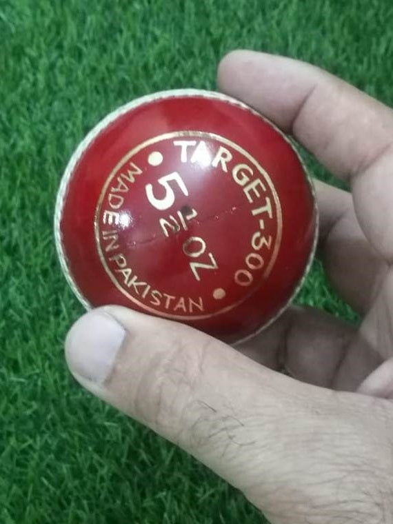 A red leather cricket ball from the "Advance Target 300 - 156g Red - Pack of 6 Balls" collection is featured against a plain white background, showcasing its prominent white hand-stitching. The ball boasts the brand name "ADVANCE" engraved in gold letters on one side, emphasizing its premium quality.