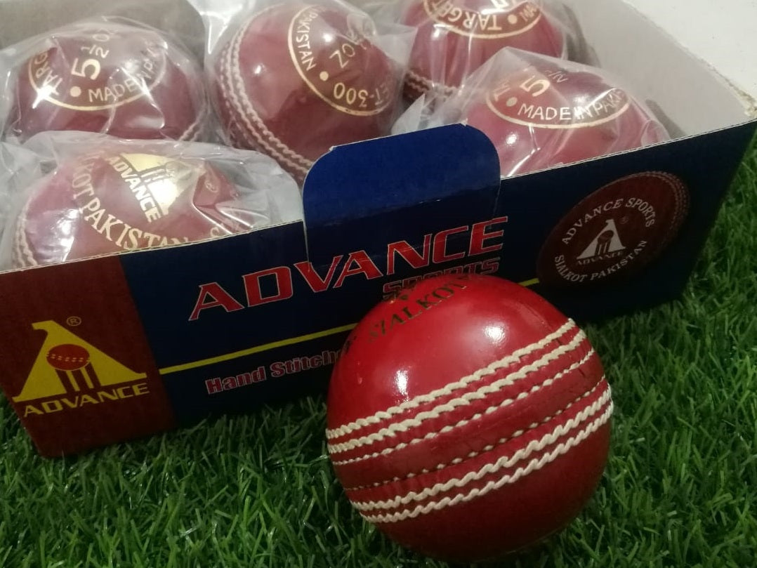 A red leather cricket ball from the "Advance Target 300 - 156g Red - Pack of 6 Balls" collection is featured against a plain white background, showcasing its prominent white hand-stitching. The ball boasts the brand name "ADVANCE" engraved in gold letters on one side, emphasizing its premium quality.