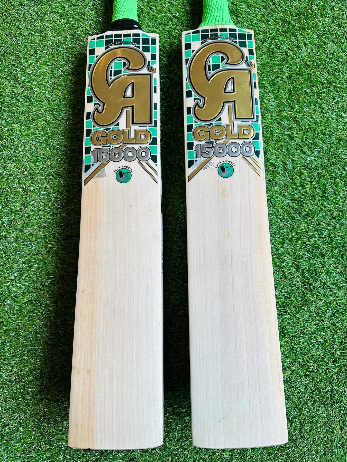 A CA Gold 15000 - Professional Standard Pro Grade English Willow cricket bat featuring a light wooden blade and a bright green handle. The front of the bat displays "CA Gold 15000" in bold, gold lettering, while the top of the blade showcases a small green and black pattern. Crafted from premium materials for superior performance.