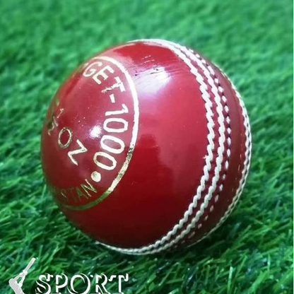 A close-up of a red leather cricket ball from the Target 1000 Super Test pack by Advance, featuring prominent white hand-stitched seams. The ball appears new and shiny with gold lettering partially visible around its circumference, displaying "STA" and "ADVAN.